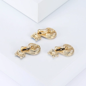 Detailed back view of three gold cat brooches showing secure safety pin fasteners