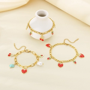 Gold strawberry and cherry charm bracelet set with red enamel on a Figaro chain