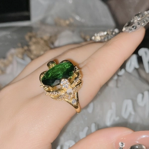 Close-up of luxury 18k gold-plated ring with a large oval green gemstone on a finger