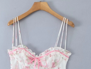 Close-up of floral camisole top with pink rose print, ruffles and delicate ribbon bow