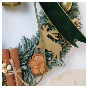 Detail of Christmas wreath with pine needles, golden reindeer, cinnamon, and velvet ribbon