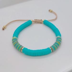 Detail of mint green heishi beads and golden spacers on adjustable woven bracelet