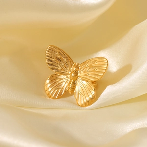 Macro shot of gold butterfly ring with detailed wing textures on champagne satin fabric
