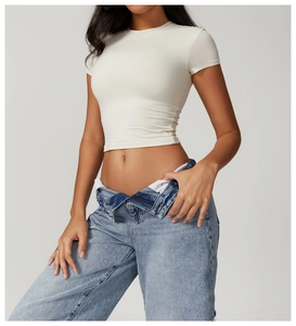 Detail of a beige slim-fit crop top paired with stylish fold-over waist light blue jeans