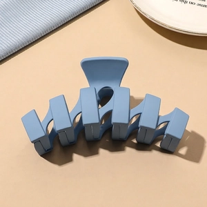 Close-up of matte light blue claw clip with five-tooth interlocking design on a desk