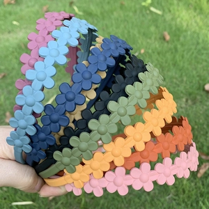 Matte flower headbands in assorted candy colors held outdoors on a grass background