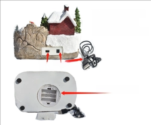 Détail d'une maison de Noël montrant l'alimentation par câble USB ou par 3 piles de type AA