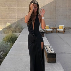 Detail of elegant black deep V-neck backless halter dress with ruched side and high slit