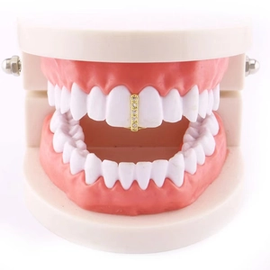 Single gold grillz with sparkling zircons on top tooth model in minimalist white background