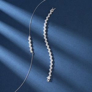 Close-up of sparkling zircon necklace and bracelet set on elegant blue fabric