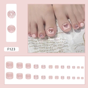 Detail of pink press-on toenails with glitter heart designs and shimmering sequins