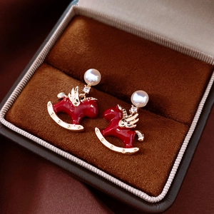 Detail of gold-plated red rocking horse earrings with pearl stud and rhinestone wings