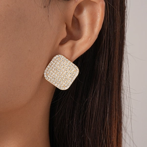 Close-up of square gold earring with pavé diamonds on model with dark hair