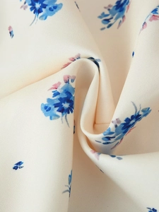 Détail du tissu à fleurs avec des motifs bleus et roses sur un fond beige clair