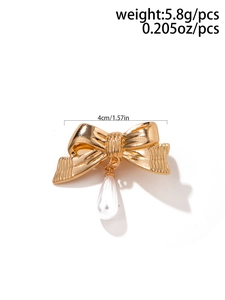 Détail de la broche dorée à double nœud avec perle blanche et largeur de 4cm