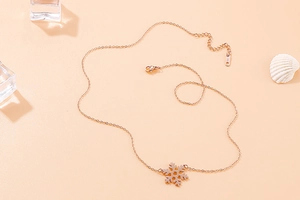 Detailed view of rose gold snowflake necklace on elegant pink background with crystals