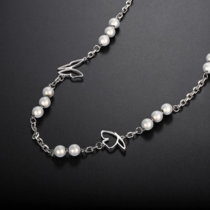 Close-up of titanium steel necklace with reflective pearls and butterfly pendant charm