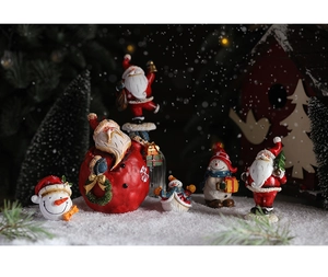 Close-up of resin Santa Claus and snowman figurines on snow with festive light bokeh
