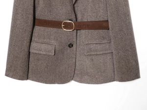 Detailed view of grey herringbone blazer with suede belt and golden metal buckle