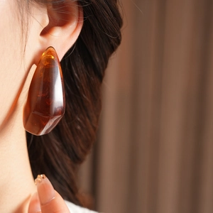 Close-up of amber resin geometric earrings worn by a model for a luxury vintage aesthetic