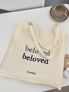 Minimalist cream canvas tote bag with beloved embroidery, styled with lifestyle props
