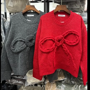 Detail of knit sweater showing textured cable knit fabric and 3D bow decoration