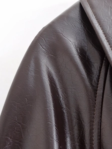 Detailed macro view of stitching and texture on dark brown leather jacket neckline
