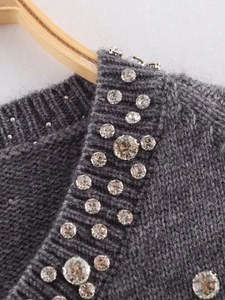 Close-up of grey knit fabric featuring intricate rhinestone embellishments on the neckline