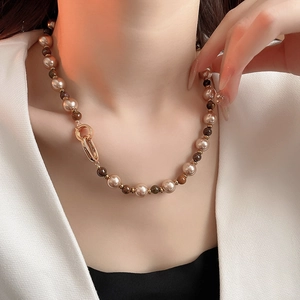 Close-up of elegant gold-plated necklace with brown beads and pearls on neck