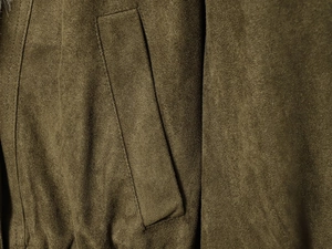 Detailed close-up of stitching and pockets on brown faux suede winter jacket