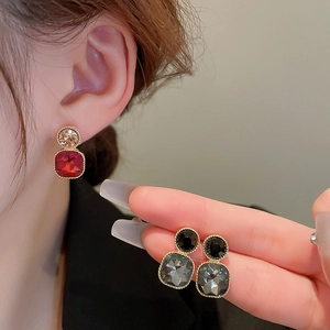 Detailed view of geometric gemstone earrings in red and black with gold beaded edges