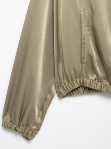 Detail of champagne satin jacket showing elastic cuffs, hem, and smooth fabric texture
