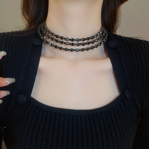 Close-up of three-layer black beaded choker necklace on model neck in dark retro style
