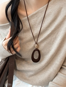 Detail of a vintage-style flocked resin pendant on a long dark brown cord necklace