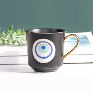 Detail of black ceramic evil eye mug with a luxurious golden ring handle and ethnic pattern