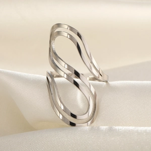Gros plan détaillé d'une bague ondulée argentée minimaliste sur satin blanc