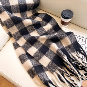 Close-up of black and white plaid scarf with fringe on a cozy beige sofa setting