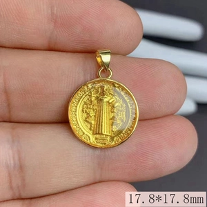 Detailed close-up of 17.8mm gold enamel Saint Benedict medallion pendant held in hand