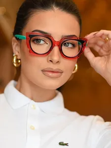 Close-up of cat-eye glasses with red translucent frames and mint green temple accents