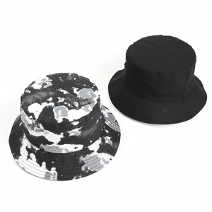 Flat lay of reversible tie-dye and solid black cotton bucket hats for sun protection