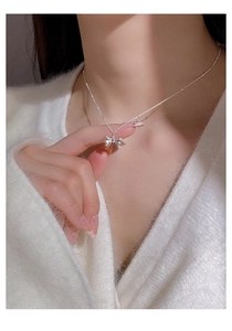 Detailed close-up of a silver bow pendant on a fine beaded S925 sterling silver chain