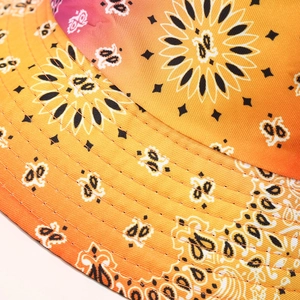 Macro detail of a tie-dye bucket hat featuring orange paisley patterns and fine stitching