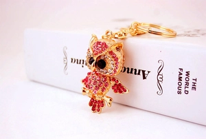 Macro shot of owl keychain with pink rhinestones on a gold metal base and key ring