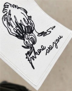 Macro detail of white fabric patch with black 'Where are you' embroidery and stitched edges