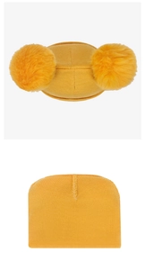 Détail du bonnet tricoté jaune pour bébé avec texture douce et deux pompons en fourrure