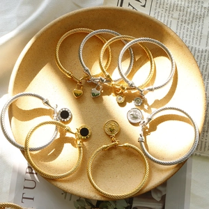 Golden and silver twisted cable bracelets with assorted heart and coin charms in a tray