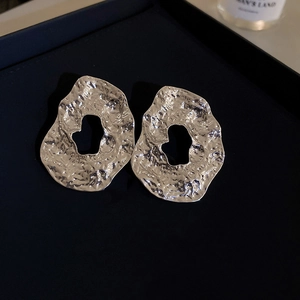 Macro shot of silver irregular geometric earrings with a hammered metal texture finish