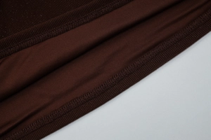 Macro shot of brown knitted fabric texture and neat industrial stitching seams on top