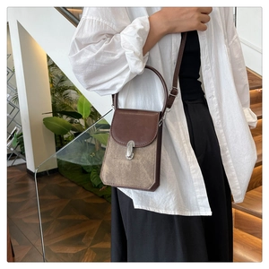 Detail of a brown leather and beige suede square crossbody bag with silver buckle