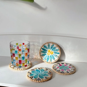 Detail of round shell mosaic coasters with woven rattan edges and floral patterns